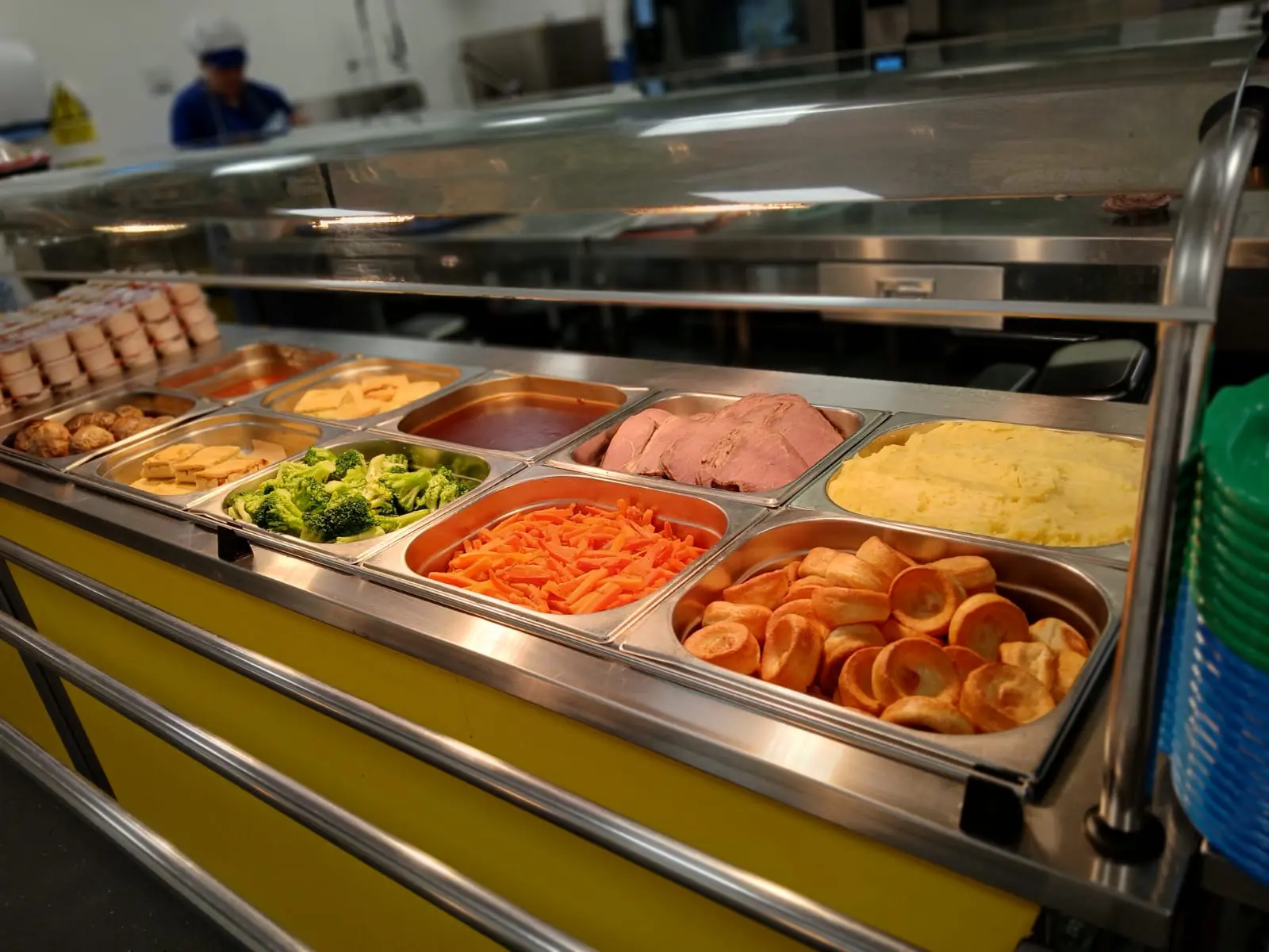 serving hot plates in a school dining hall showing varies food items including gravy, mashed potatoes, carrots